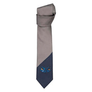 Harmaa-sininen solmio, jonka kärjessä Huuhkajat-printti.